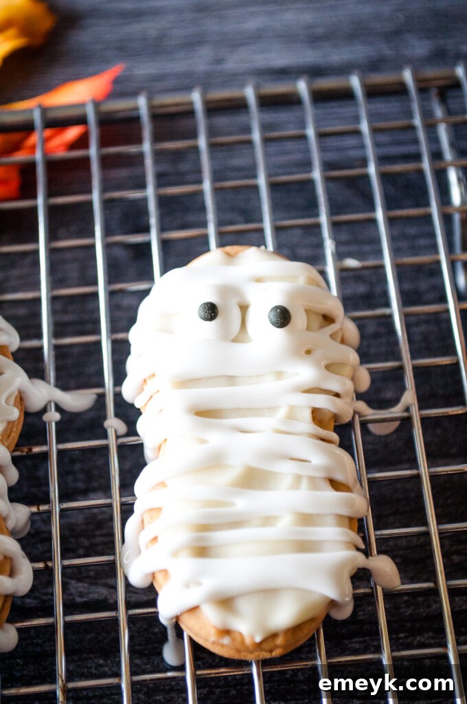 Mummy Cookies arranged on a cookie sheet, showcasing their cute and spooky design with candy eyes and white frosting bandages.