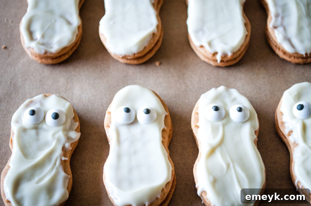 Mummy Cookies with their candy eyes placed, waiting for the frosting bandages to be added, on a cooling rack.