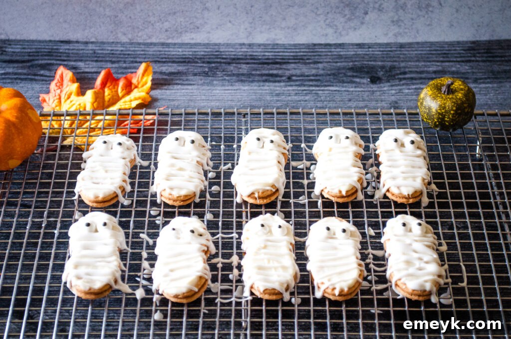Finished Mummy Cookies with complete frosting bandages and candy eyes, artfully arranged on a cooling rack.