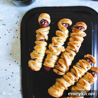 Mummy Hot Dogs on black plate, a delicious and easy Halloween recipe.