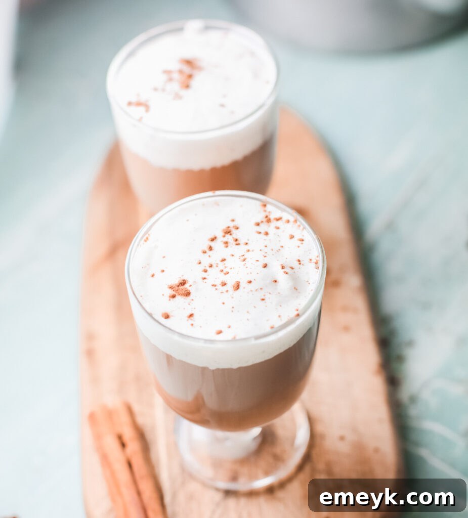 Instant Pot Spiced Chai Latte 3 Two cups of Instant Pot Chai Tea Latte, one topped with frothy milk and a sprinkle of cinnamon, the other with cinnamon whipped cream.