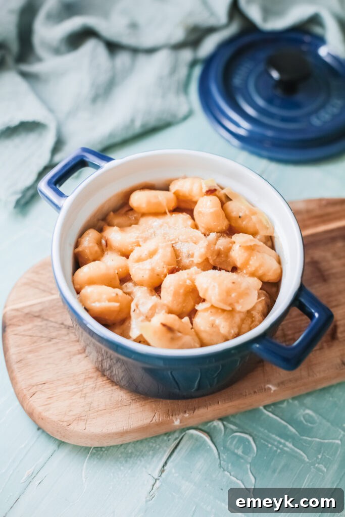 A blue bowl filled with One Pot French Onion Gnocchi, garnished with fresh parsley and melted cheese.