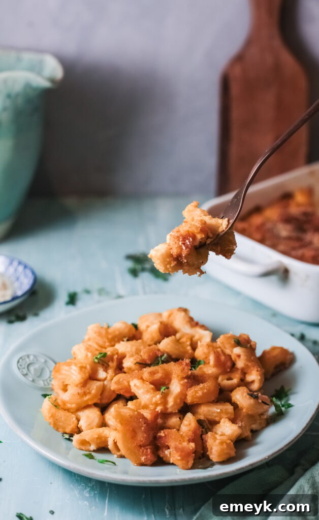 A fork taking a scoop of Pumpkin Mac and Cheese from a bowl, showcasing its creamy texture.