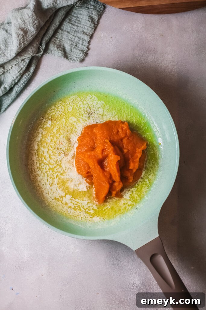 Pumpkin puree cooking with spices in a saucepan, darkening in color.