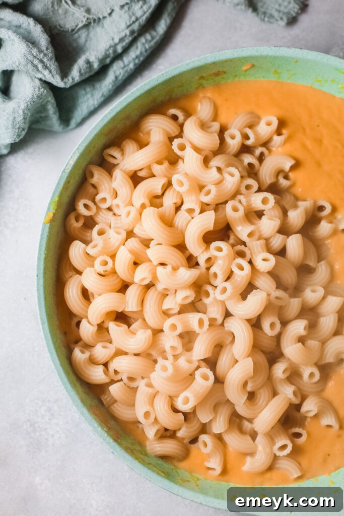 Creamy pumpkin sauce thickening in a saucepan, ready for pasta and cheese.