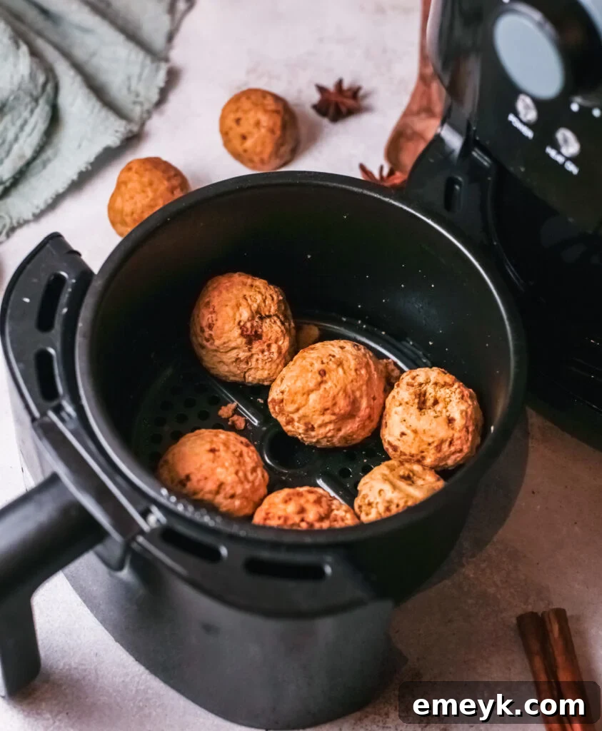 Pumpkin Donut Holes cooking in an air fryer basket, showing their golden-brown texture.