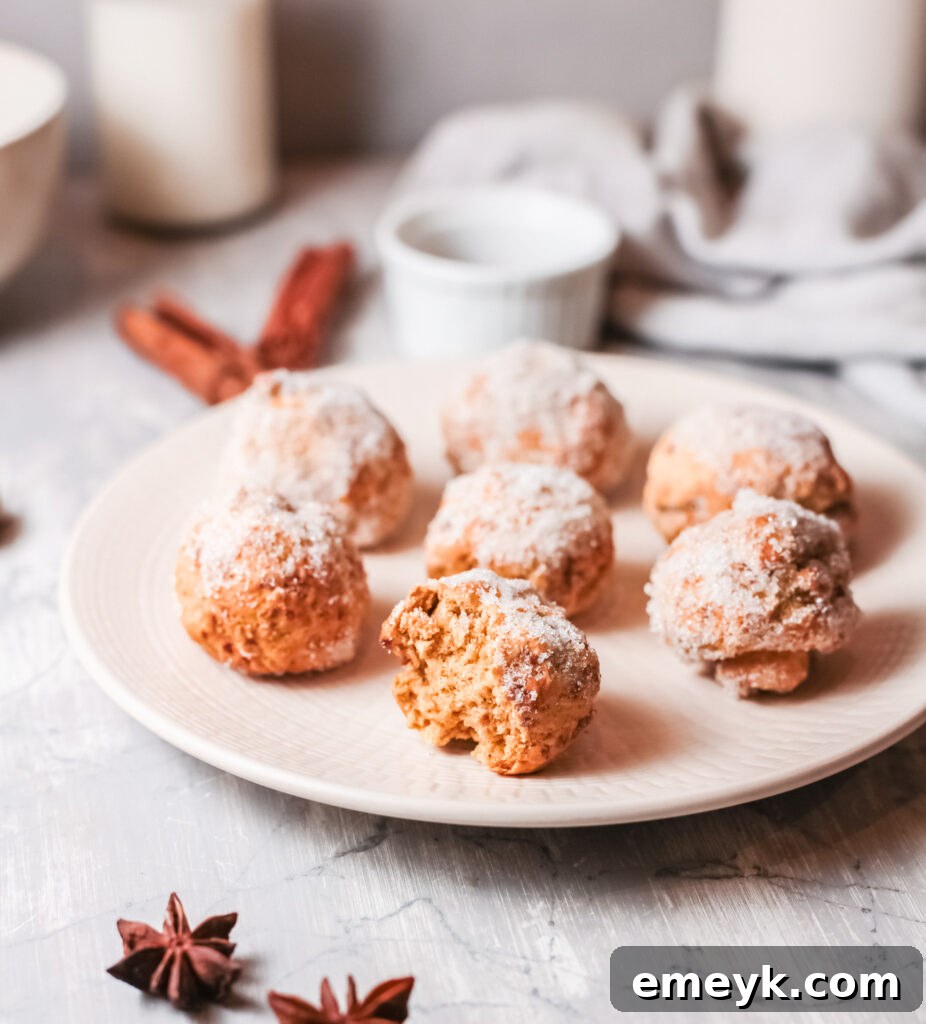 Freshly made Air Fryer Pumpkin Donut Holes, coated in cinnamon sugar, arranged on a white plate.