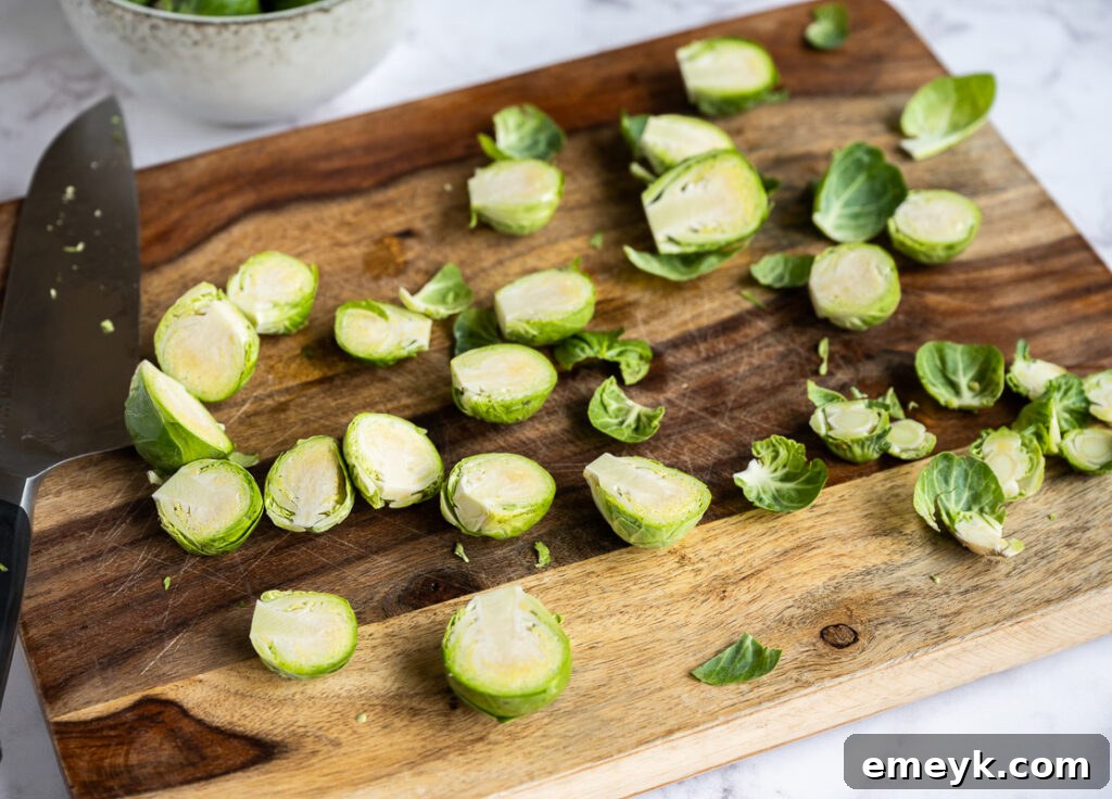 Prepared Brussels sprouts, cut in half and ready for roasting, displayed on a wooden cutting board.