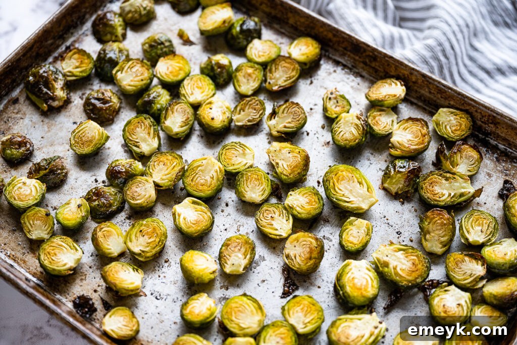 Roasted Brussels sprouts, golden-brown and slightly charred, fresh out of the oven, piled onto a serving dish.