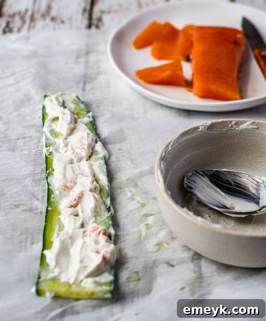 Spreading goat cheese mixture onto a thinly sliced cucumber strip