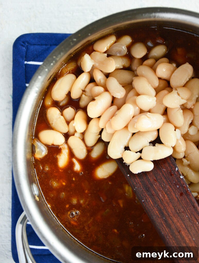 Easy Bacon Baked Beans simmering in a pot, ready for the oven.
