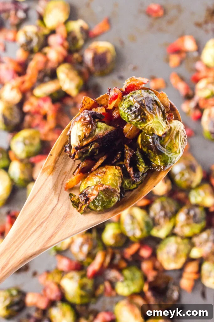 A close-up shot of perfectly roasted Brussels sprouts with crispy bacon bits served on a spoon, highlighting their golden-brown color and irresistible texture.
