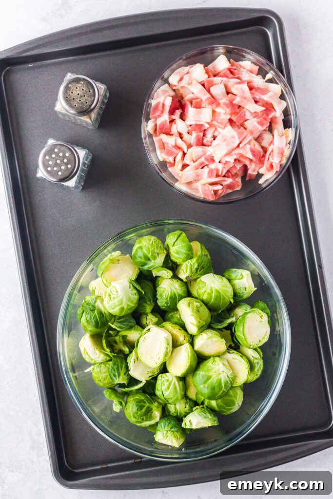 Key ingredients for Roasted Brussels Sprouts with Bacon: fresh green Brussels sprouts, strips of raw bacon, garlic cloves, and olive oil on a wooden board.