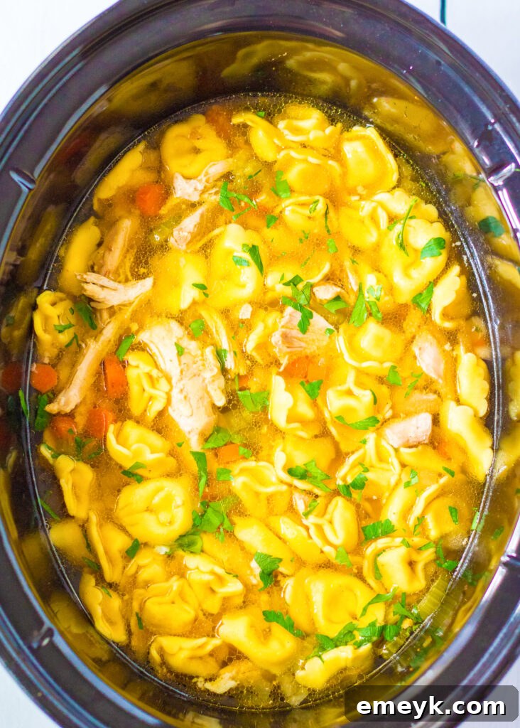 Comforting Chicken Tortellini Soup 4 Chicken Tortellini Soup simmering gently in a slow cooker, filling the kitchen with inviting aromas.