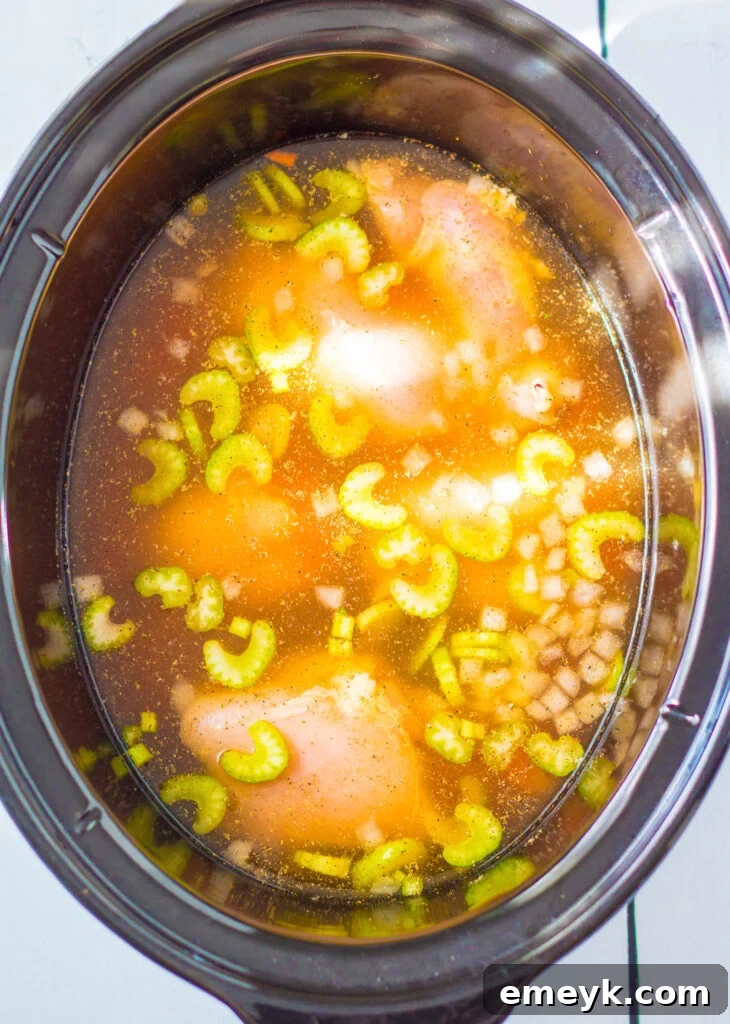 Comforting Chicken Tortellini Soup 5 The slow cooker with vegetables, broth, and chicken thighs, ready to be cooked.