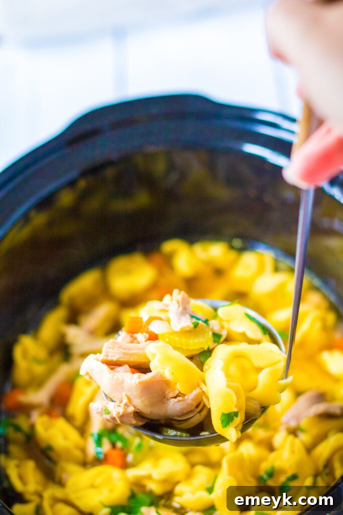 Comforting Chicken Tortellini Soup 6 Cheese tortellini being added to the slow cooker with the cooked chicken and vegetables.