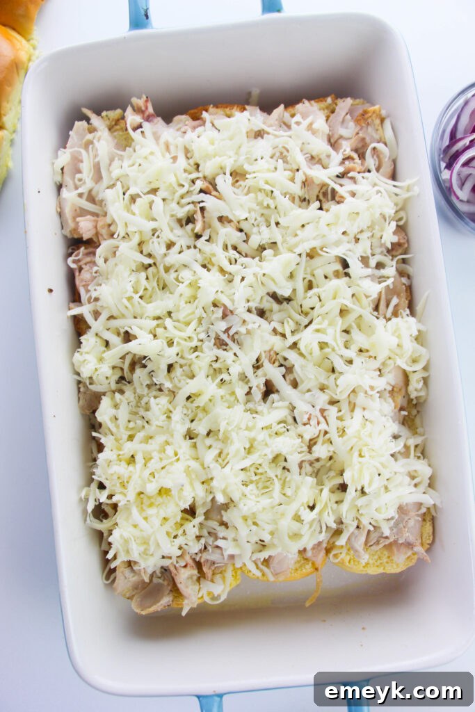 Simple Savory Chicken Sliders 9 Shredded cheese spread over chicken on slider buns
