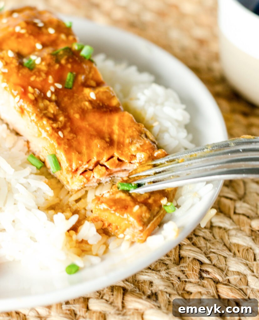Perfect Glazed Teriyaki Salmon 7 A fork taking a piece of flaky Teriyaki Salmon, showing its tender texture