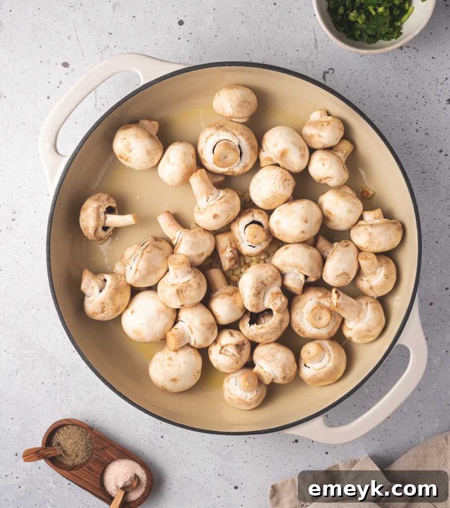 Golden Garlic Mushrooms 6 White mushrooms added to a skillet with hot oil and garlic, waiting to be seared.