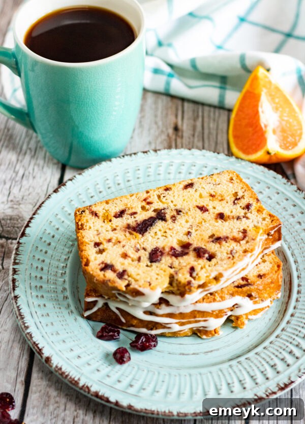Slice of Cranberry Orange Bread with cream cheese icing on a white plate.