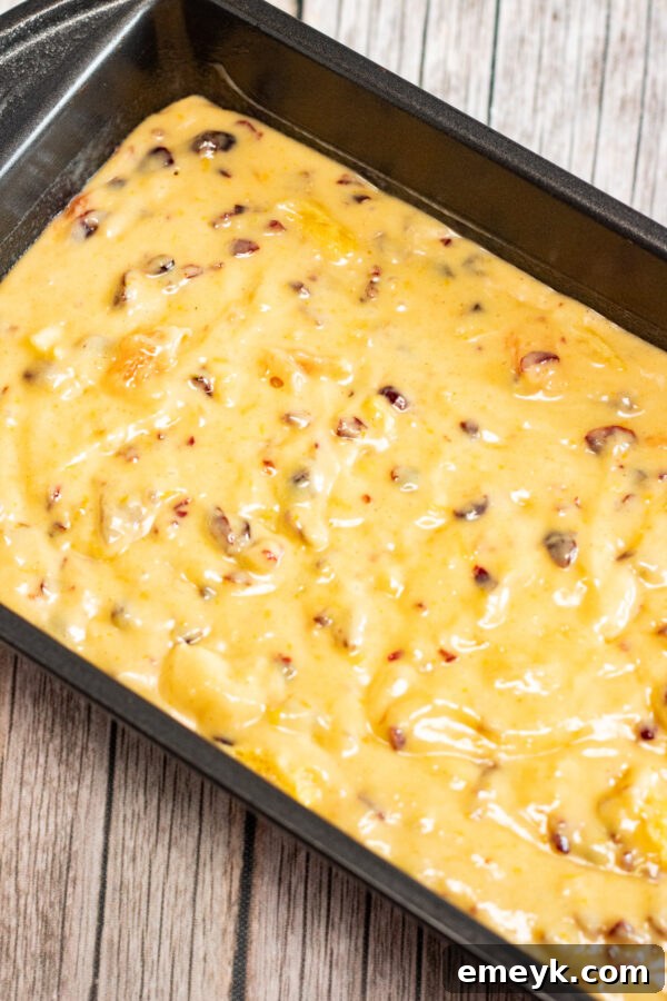 Baked cranberry bread loaf in a pan, cooling slightly.