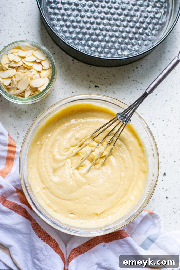 Close-up shot of a smooth, golden Honey Almond Cake batter in a large mixing bowl, ready to be poured into a baking pan.