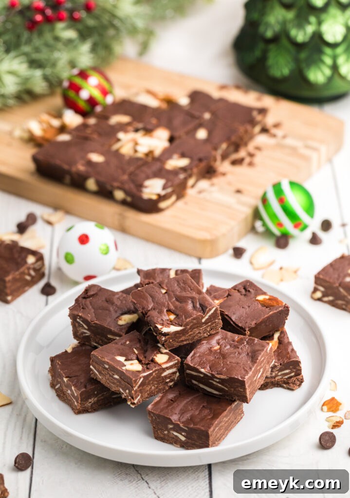 Beautifully arranged squares of easy chocolate fudge on a white plate, garnished with almonds.