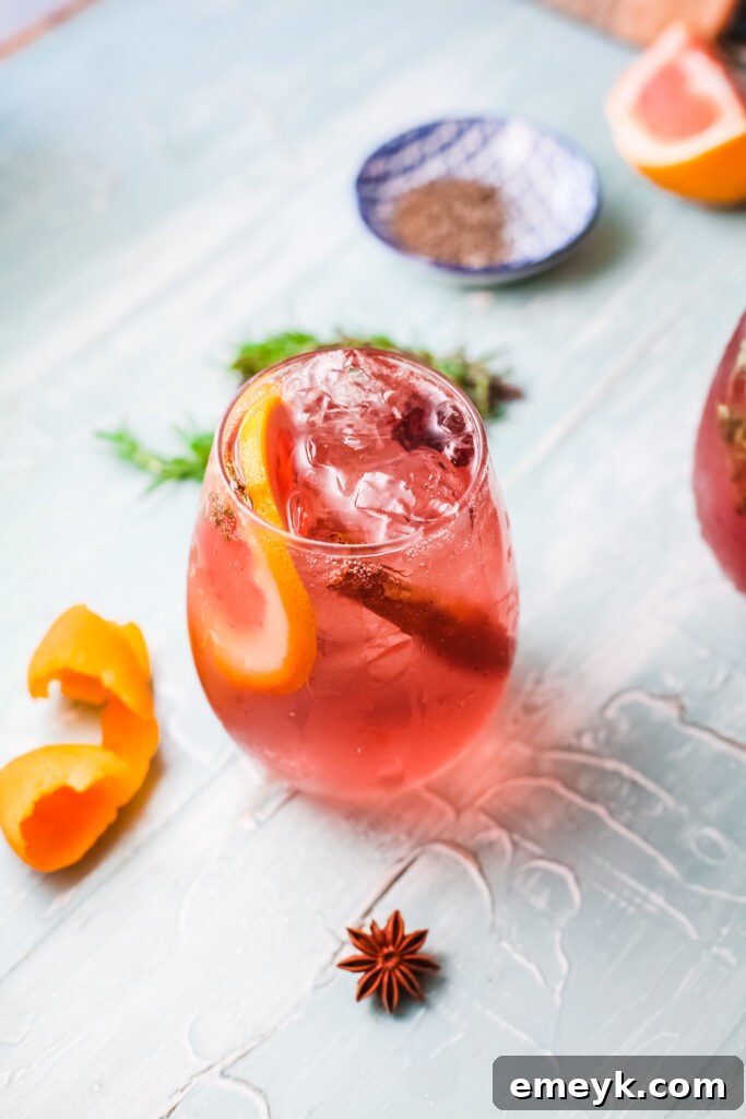 A beautifully garnished Cranberry Wine Spritzer in a tall glass, set against a festive, cozy holiday backdrop. Perfect for seasonal gatherings.