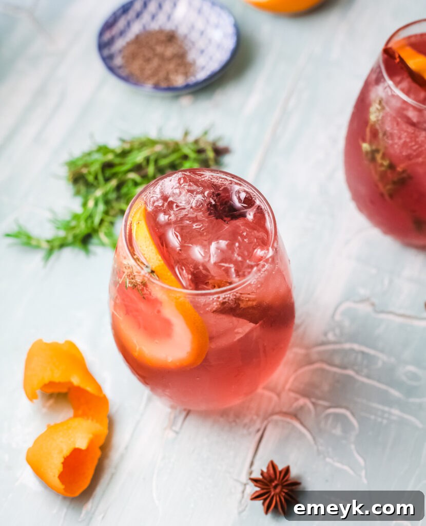 Close-up of a Cranberry Wine Spritzer, garnished with vibrant orange slices, fresh cranberries, and a cinnamon stick, highlighting its festive appeal.