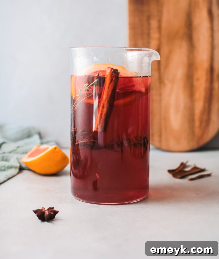 A large, inviting pitcher overflowing with Cranberry Wine Spritzer, beautifully garnished and ready to refresh a crowd at a holiday gathering.