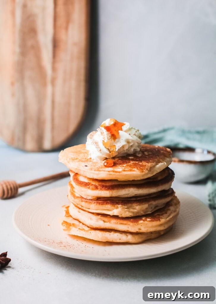 Fluffy Eggnog Pancakes stacked with whipped cream and maple syrup, perfect for a holiday breakfast