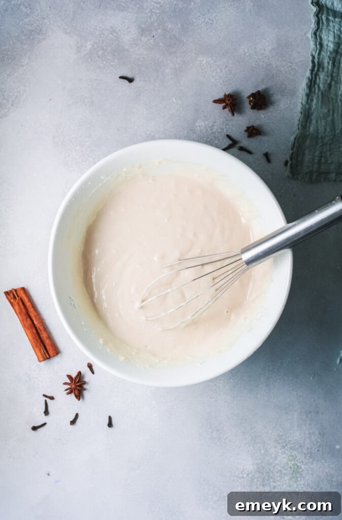 Bowl of Eggnog Pancake batter with a whisk, showing the creamy texture and hint of nutmeg