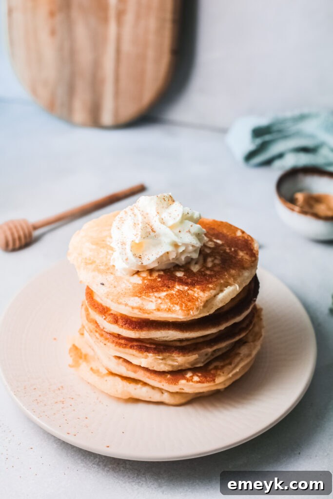 Stack of warm Eggnog Pancakes drizzled with maple syrup, ready to be enjoyed