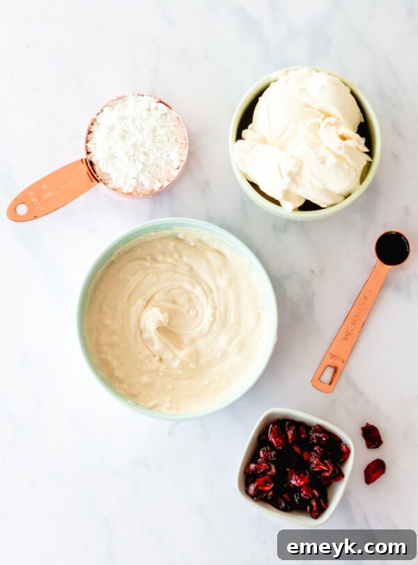 All the fresh and dry ingredients for Cranberry Bliss Bars laid out on a clean counter, including flour, sugars, butter, eggs, cranberries, and white chocolate.