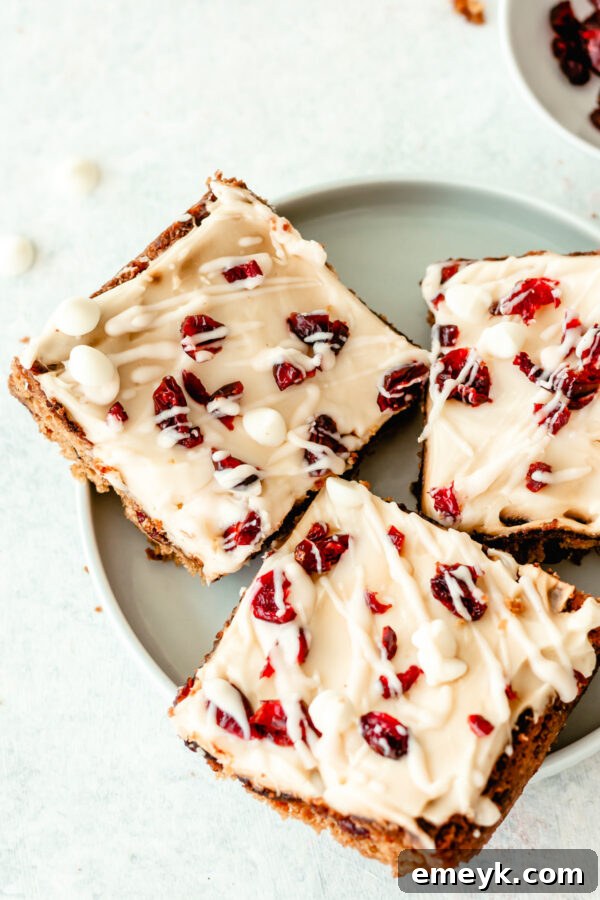 A perfectly cut Cranberry Bliss Bar on a delicate plate, showcasing its rich layers of blondie, cranberries, white chocolate, and creamy frosting.
