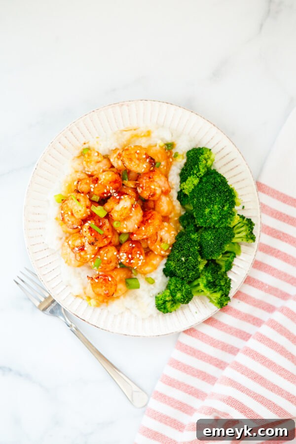 Sticky Sriracha Honey Garlic Shrimp 3 Honey Garlic Sriracha Shrimp presented beautifully on a white plate, garnished with green onions and sesame seeds.
