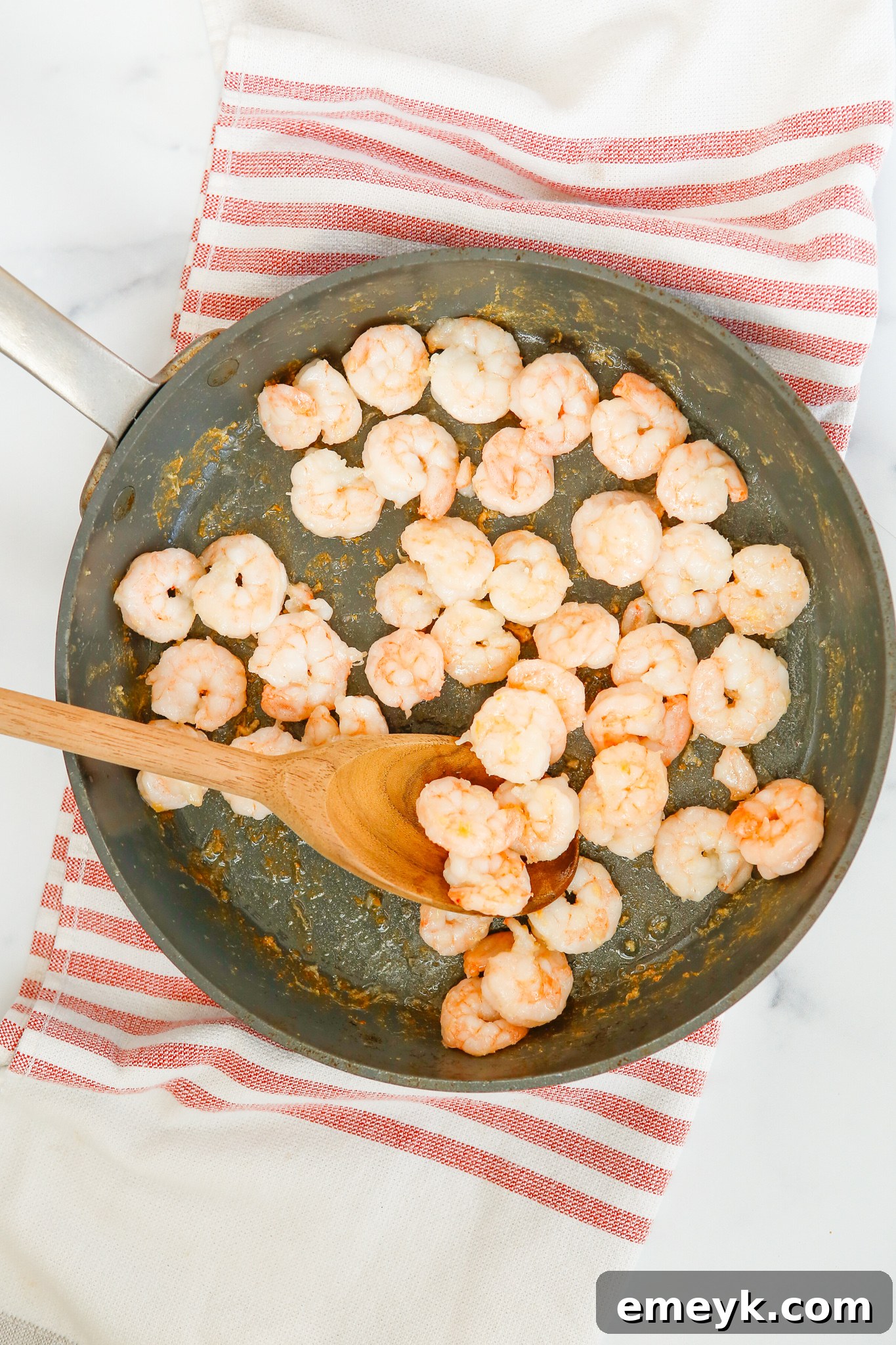Sticky Sriracha Honey Garlic Shrimp 5 Raw shrimp sizzling in a hot skillet with a touch of oil.