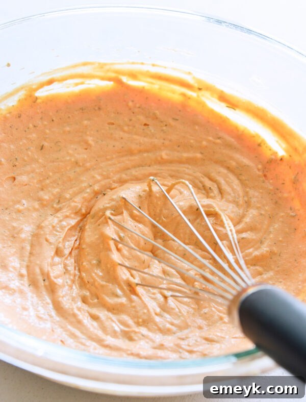 Cream cheese, sour cream, and spices being whisked together in a large bowl