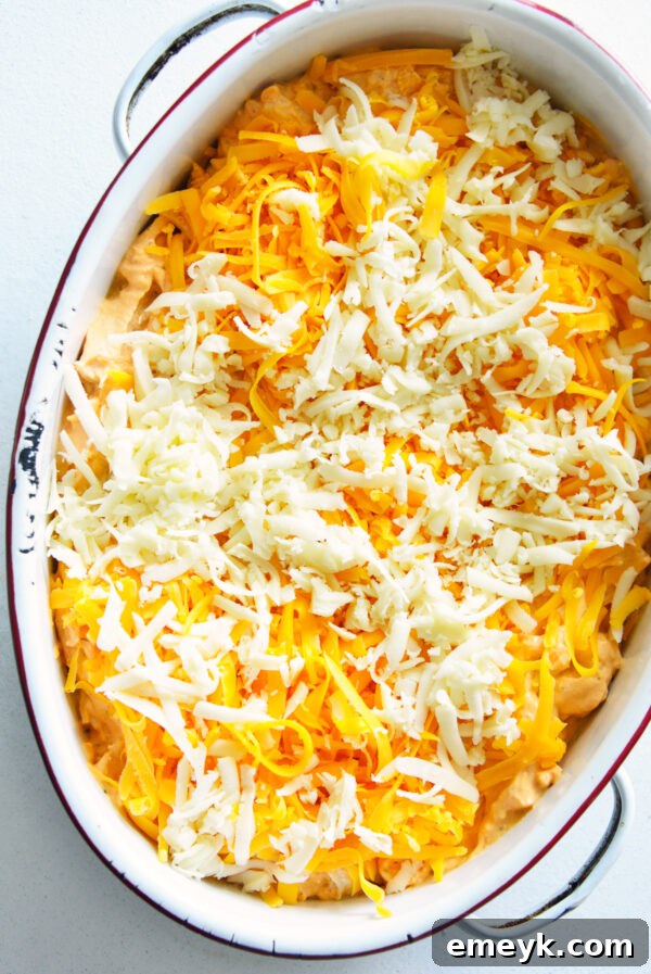 Buffalo chicken dip in a baking dish, topped with cheese, before being baked