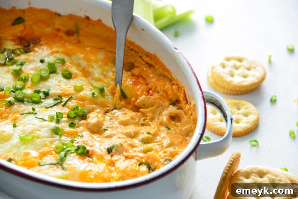 Finished Buffalo Chicken Dip in a white baking dish, garnished with fresh scallions