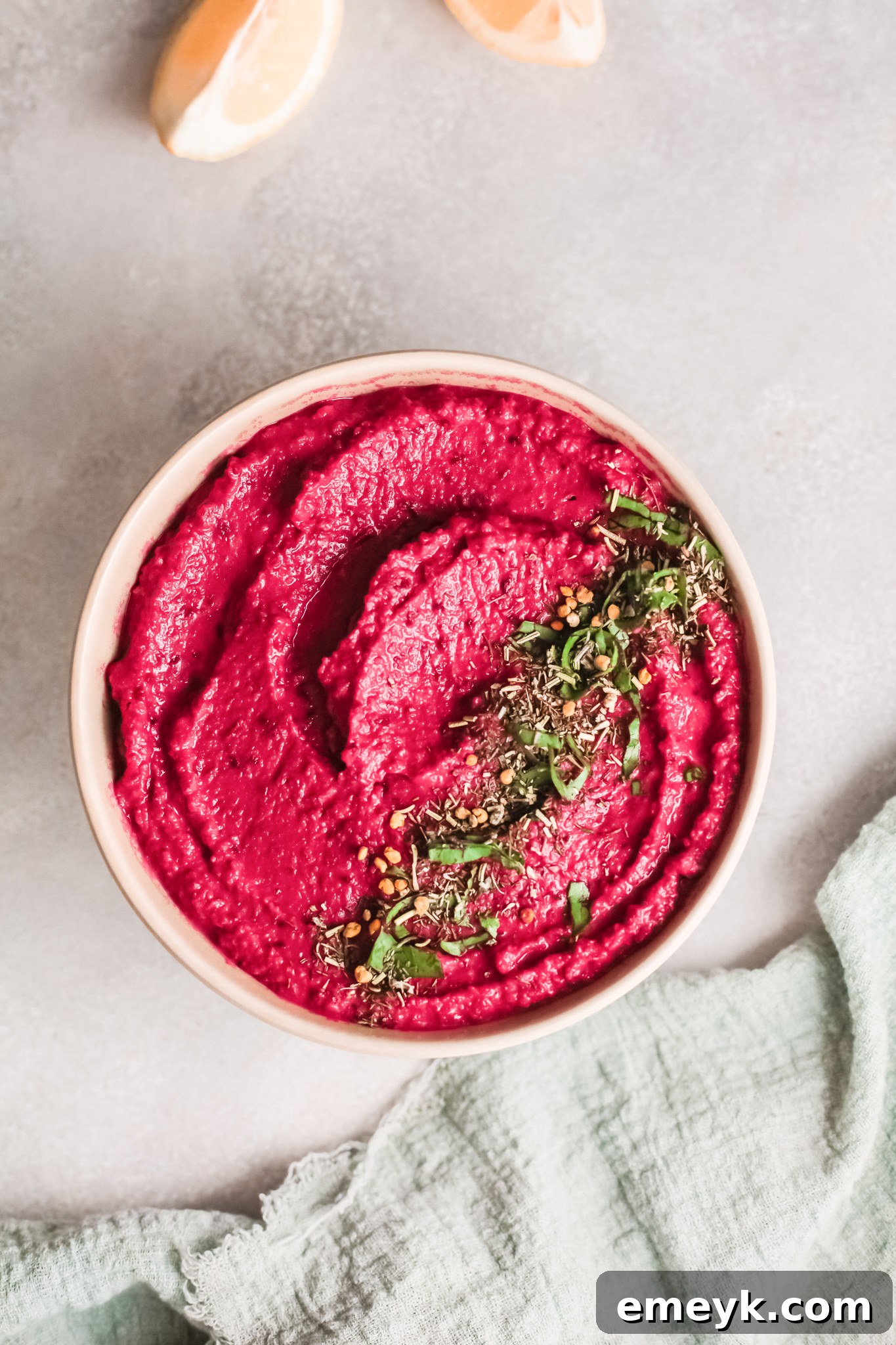 A bowl of vibrant Easy Beet Hummus topped with fresh parsley and a swirl of olive oil.