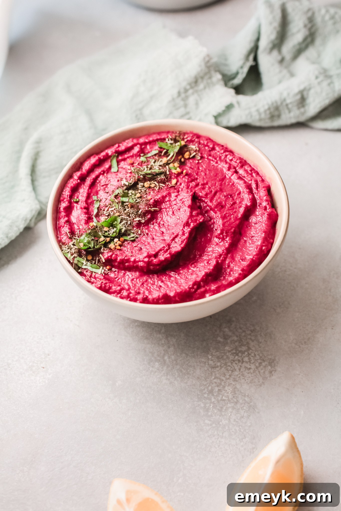 A bowl of Easy Beet Hummus, garnished and ready to serve, with a decorative napkin.