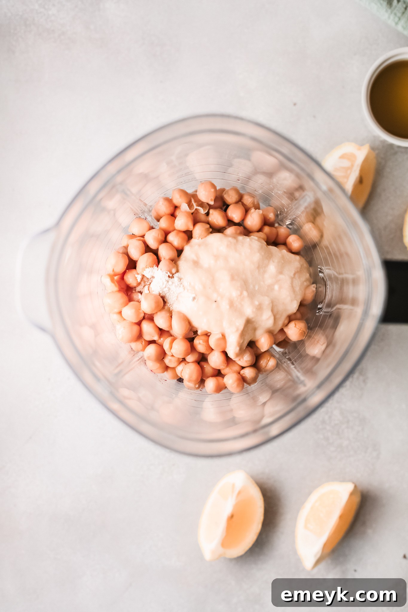 Easy Beet Hummus being blended in a food processor, with olive oil being drizzled in.