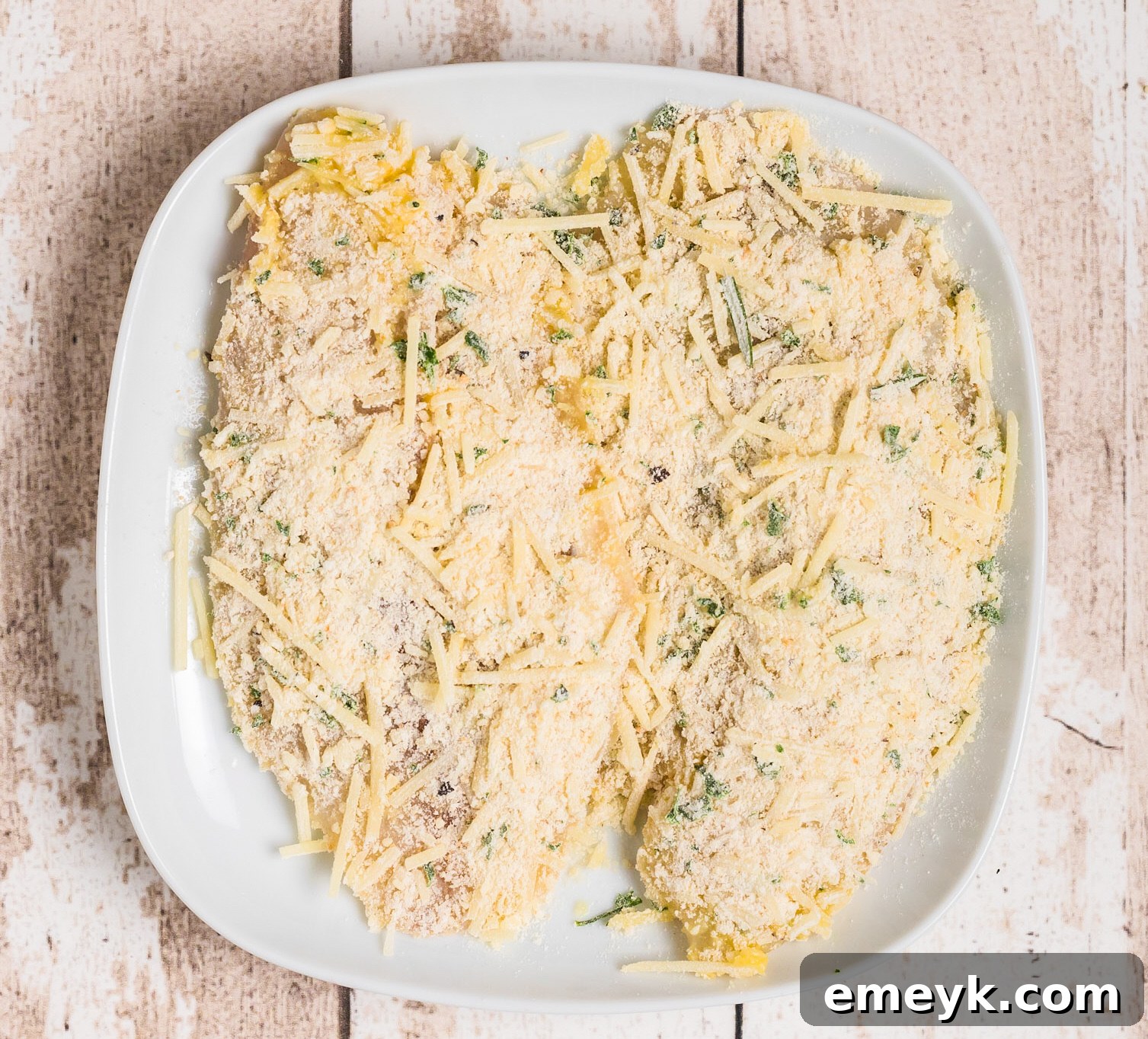 Prepared Parmesan Crusted Tilapia fillets resting on a plate, ready for pan-searing.