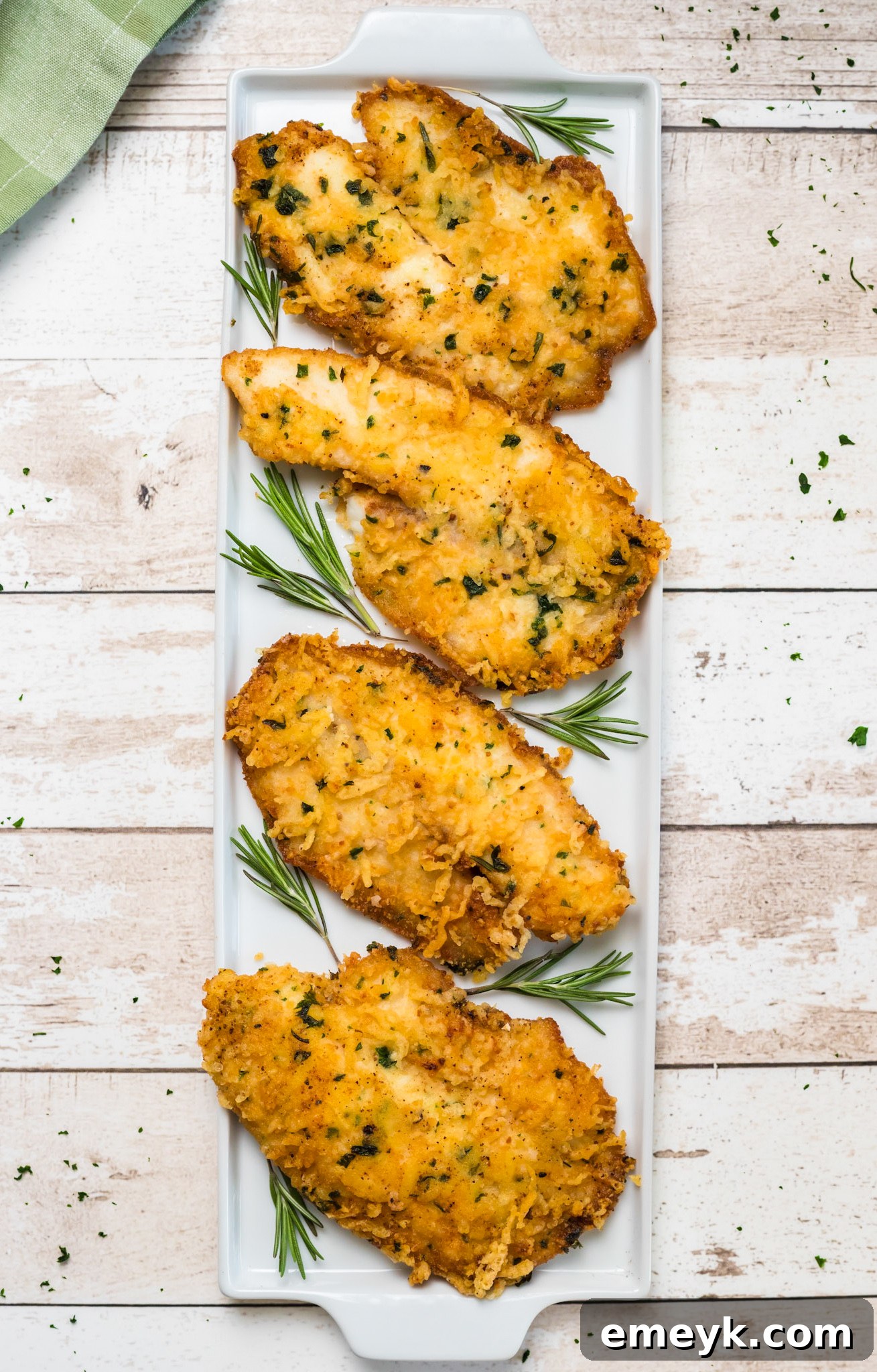 Parmesan Crusted Tilapia garnished with a sprig of rosemary.