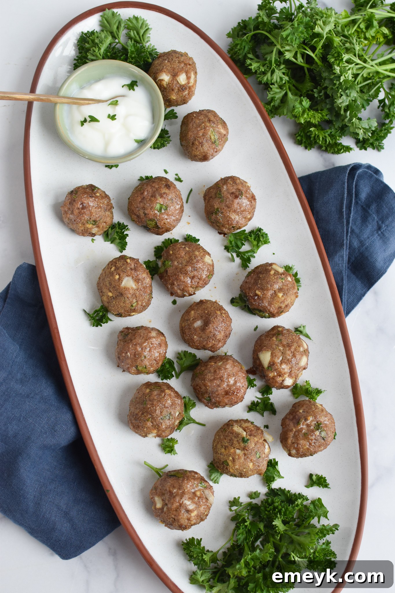 Spiced Lamb Kofta 5 Succulent Lamb Kofta arranged beautifully on a pristine white platter, garnished with fresh herbs, ready to be served as an impressive centerpiece or appetizer.