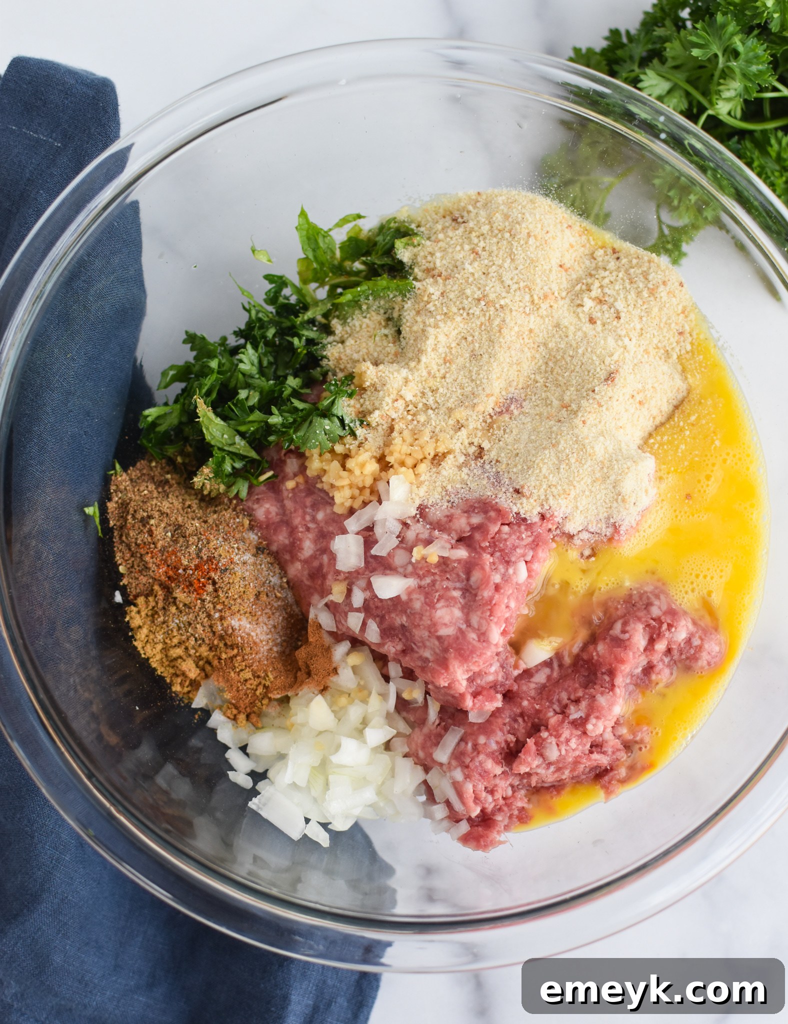 Spiced Lamb Kofta 6 All the Lamb Kofta ingredients, including ground lamb, fresh herbs, and various spices, are combined in a large mixing bowl, ready to be mixed by hand to create the flavorful meat mixture.