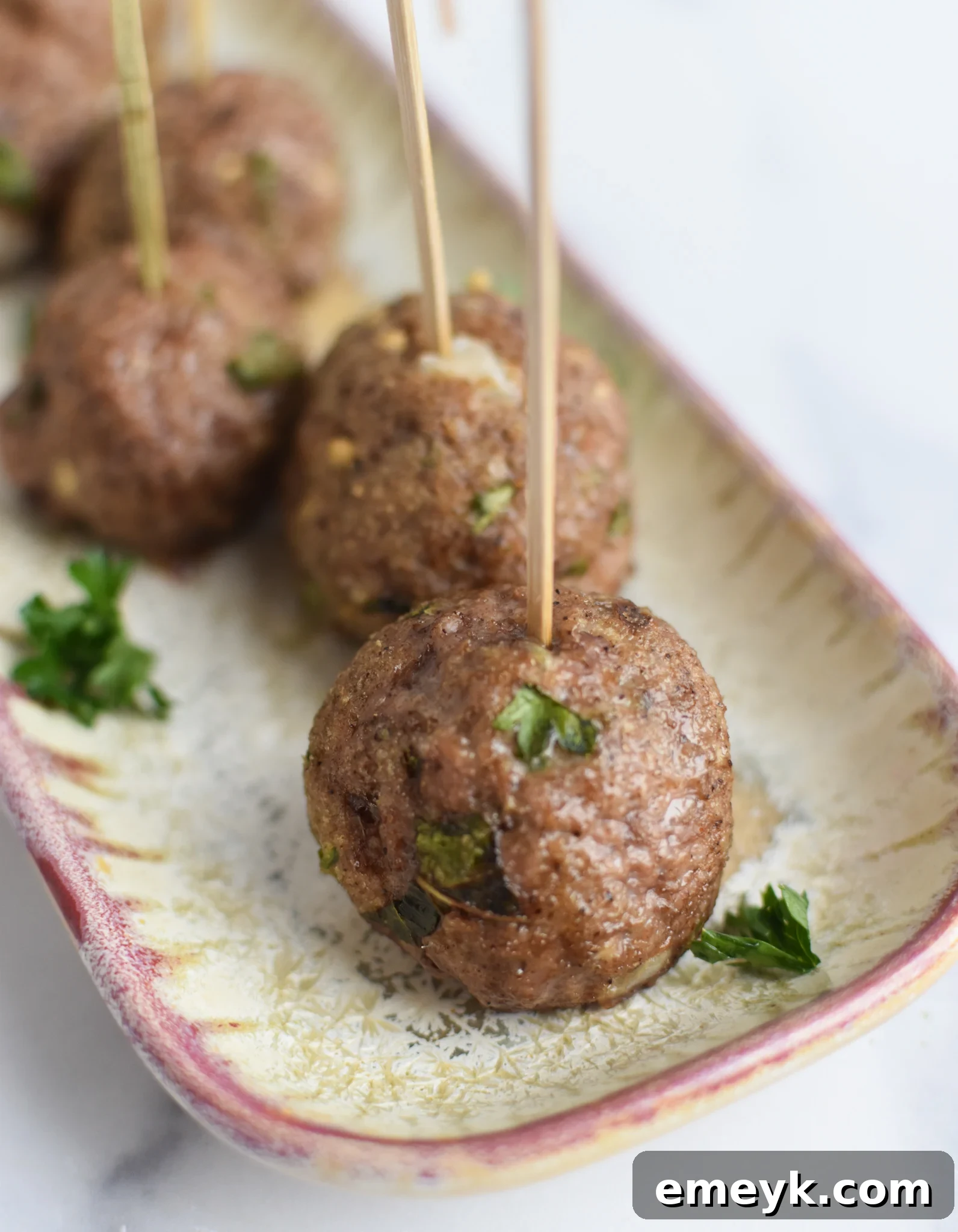 Spiced Lamb Kofta 9 An elegant appetizer platter featuring perfectly grilled Lamb Kofta, skewered with toothpicks for easy serving, surrounded by fresh herbs and lemon wedges.