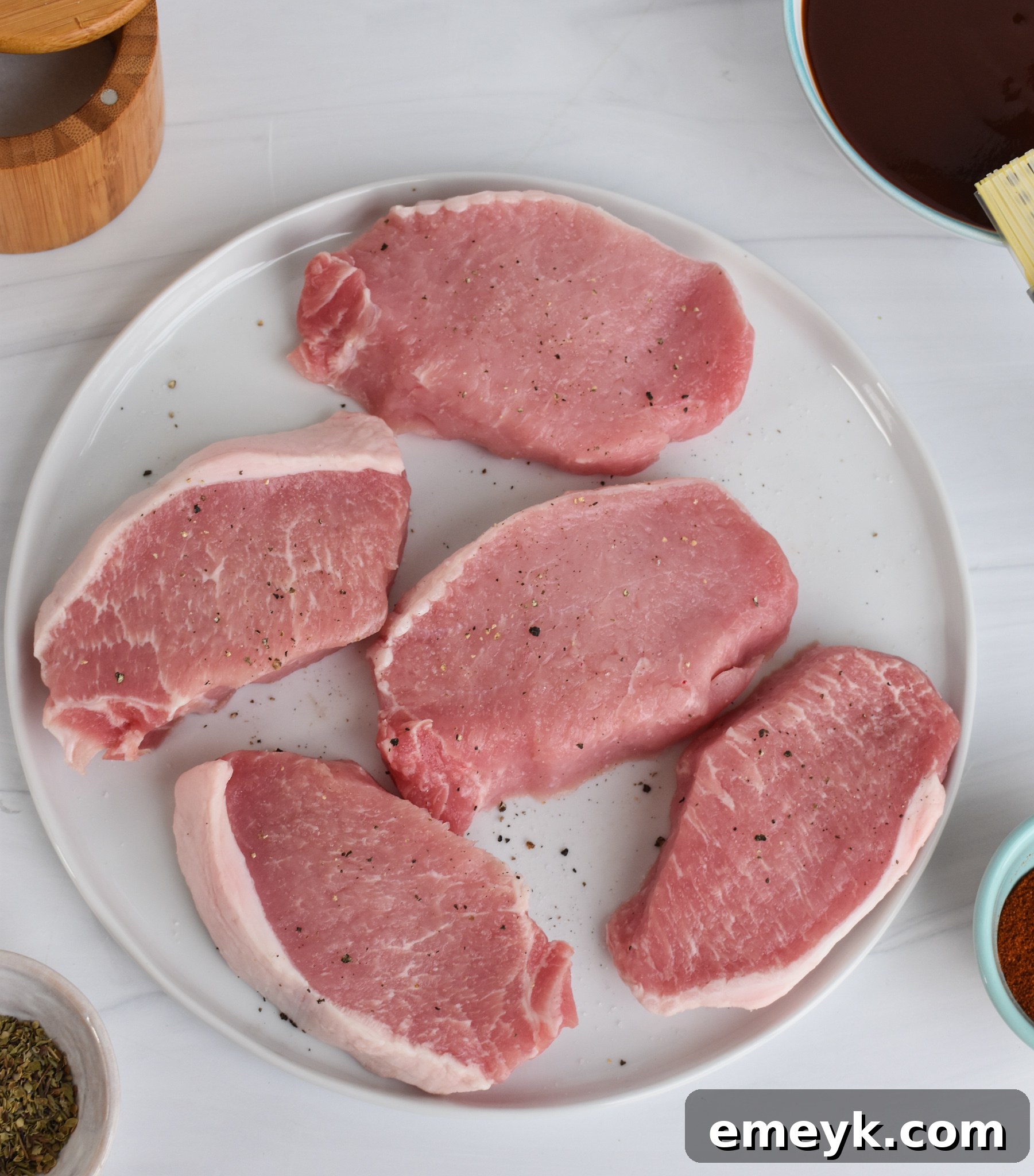Succulent Baked BBQ Pork Chops 5 Ingredients for BBQ Baked Pork Chops laid out on a wooden table.