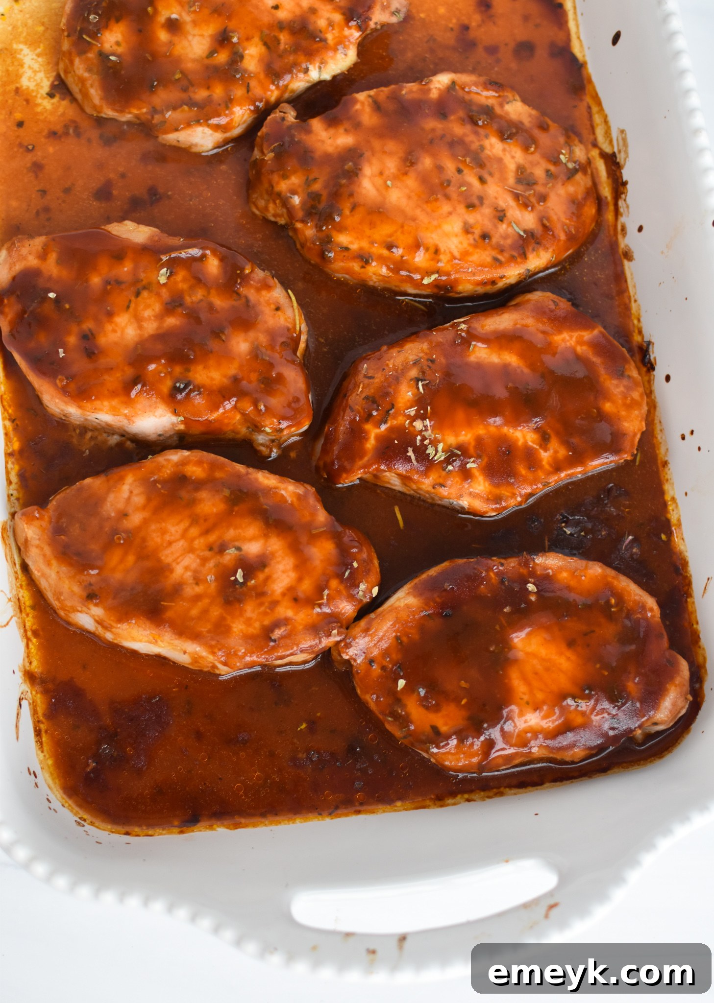 Succulent Baked BBQ Pork Chops 7 BBQ Baked Pork Chops cooking on a wire rack on a baking sheet.